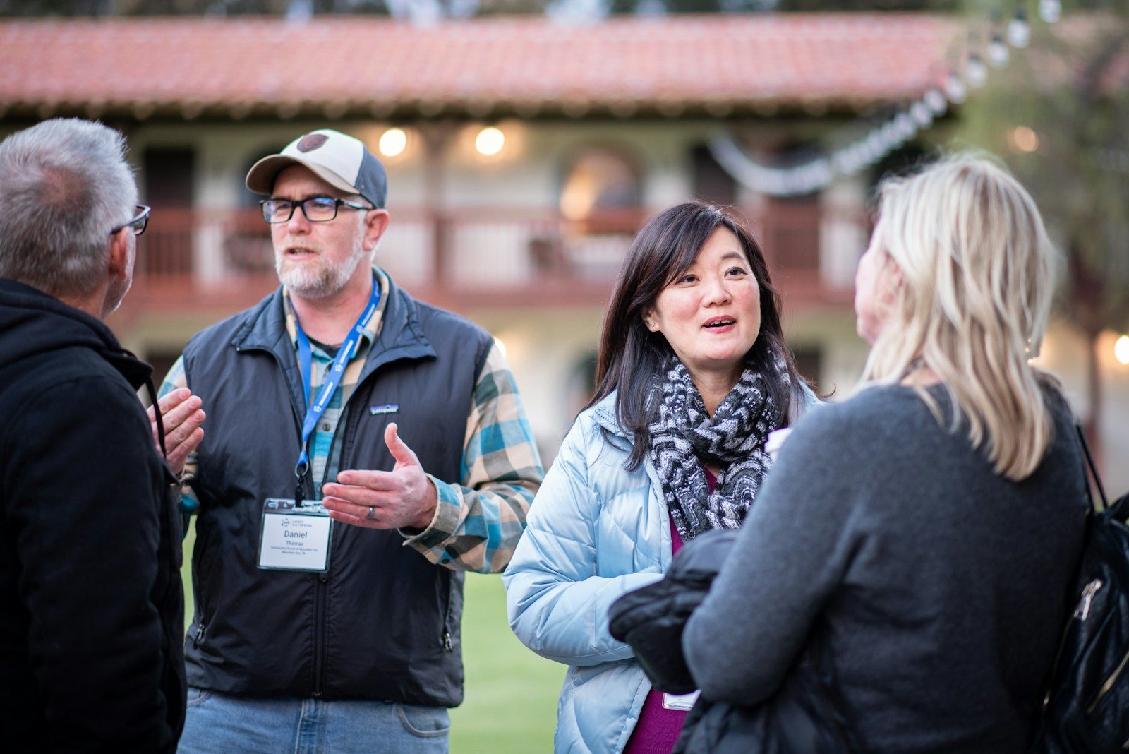 Church members of different ages standing outdoors, smiling and talking together